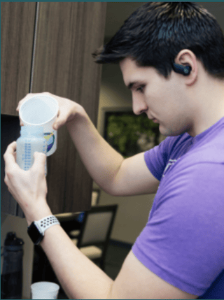 a student wearing headphones concentrating on making baby formula in a bottle