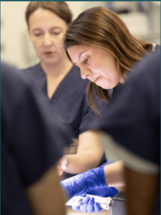 a surgeon practicing a procedure as people watch