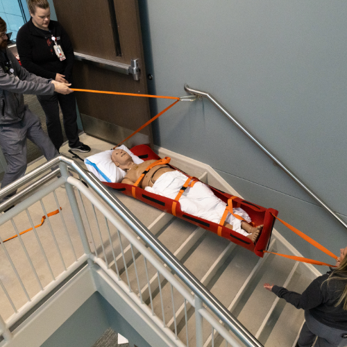 healthcare providers practicing using a stair sled with a manikin