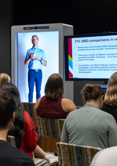 professor standing in a holographic box presenting to students in a room